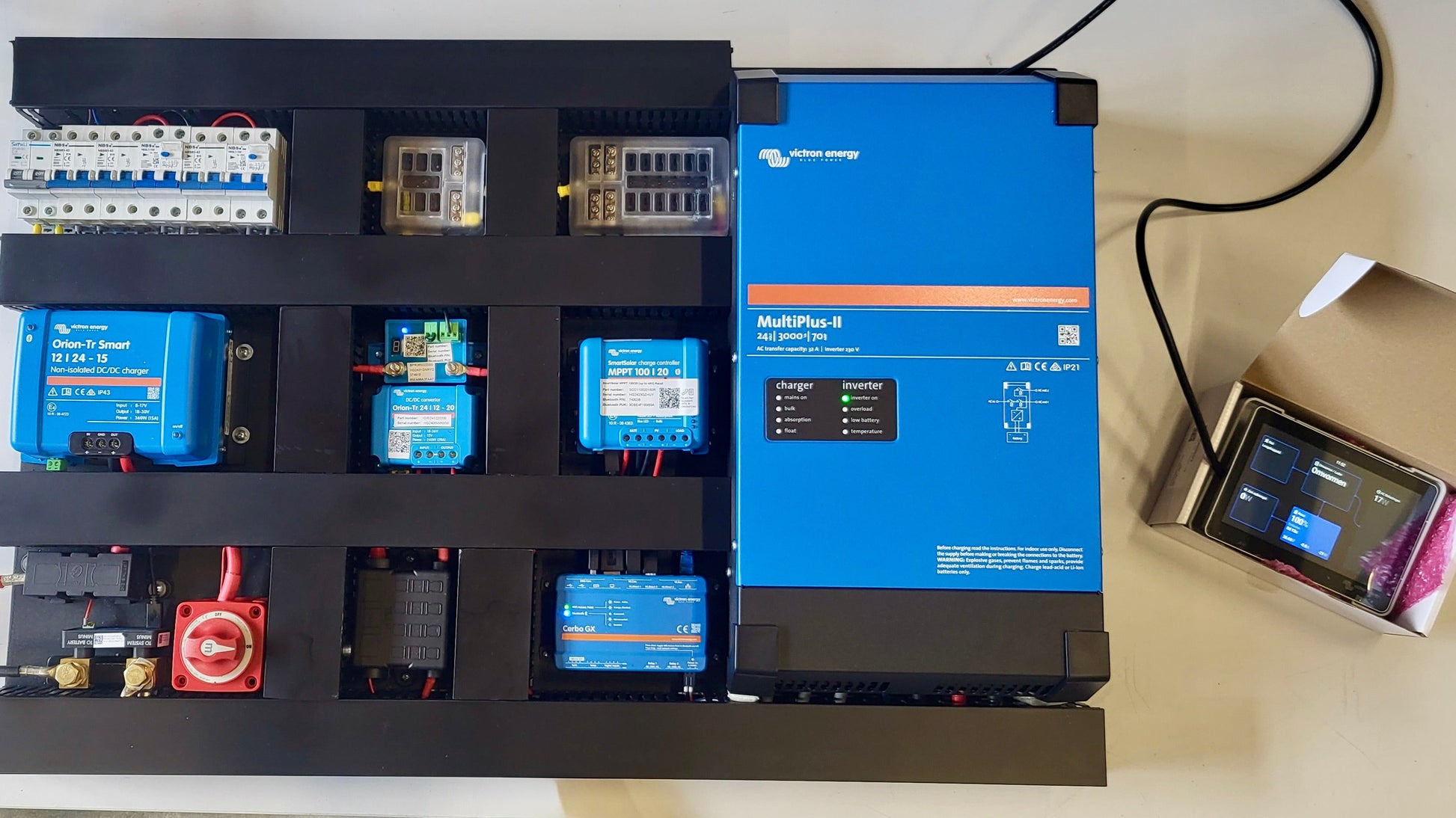 Voorgemonteerd Freedom-elektrasysteem van Faraday Energy met Victron-componenten; compleet afgemonteerd bord met bekabeling in zwarte kokers en GX Touch 70-scherm tijdens testfase.