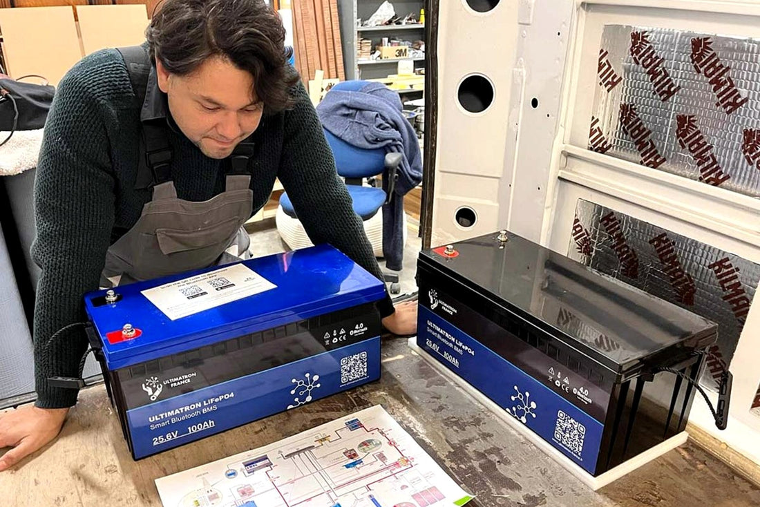 Zelfbouwer bespreekt camper-elektra installatie met technische tekening en lithiumaccu’s
